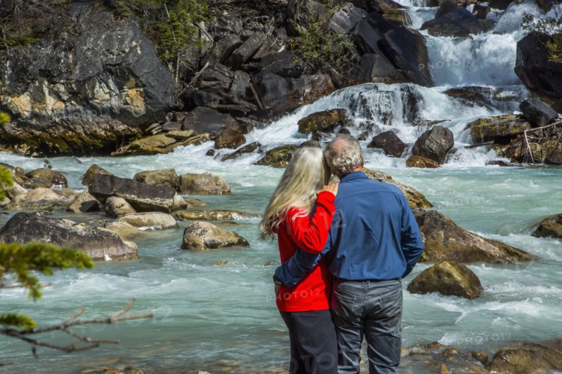 Caucasian couple admiring rapids over rocks