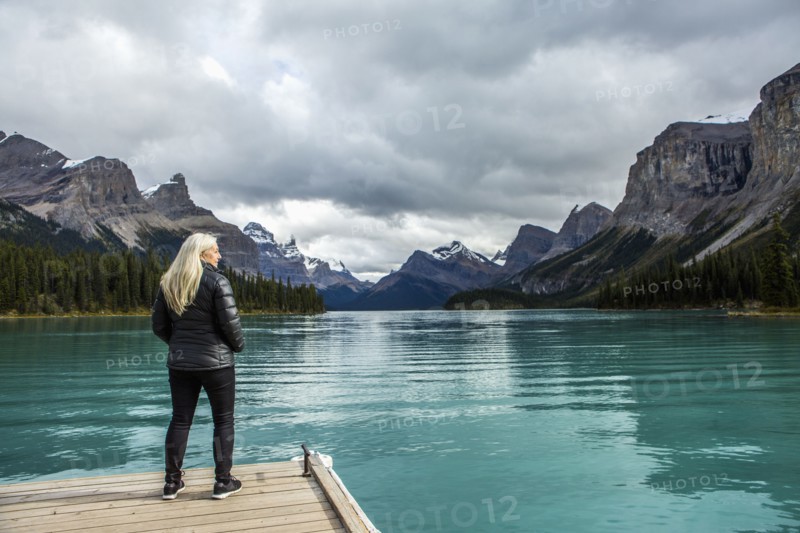 Caucasian woman standing at the end of dock on mountain lake