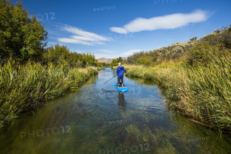 Caucasian woman paddleboarding on river