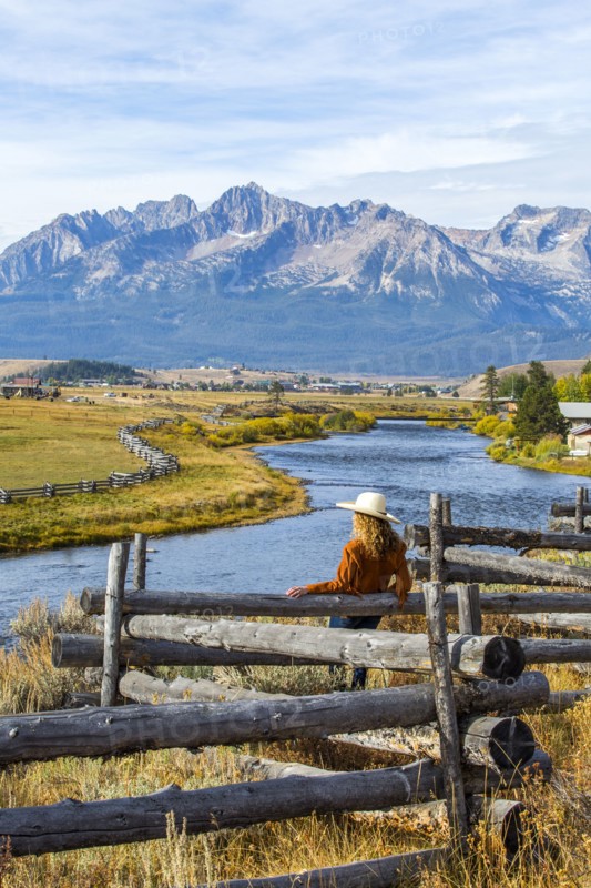 Caucasian woman leaning on wooden fence at mountain river