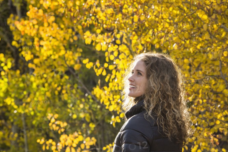 Smiling Caucasian woman under autumn leaves