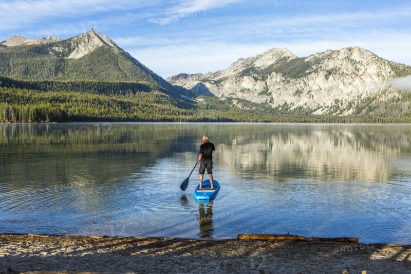 Caucasian man paddleboarding on mountain lake