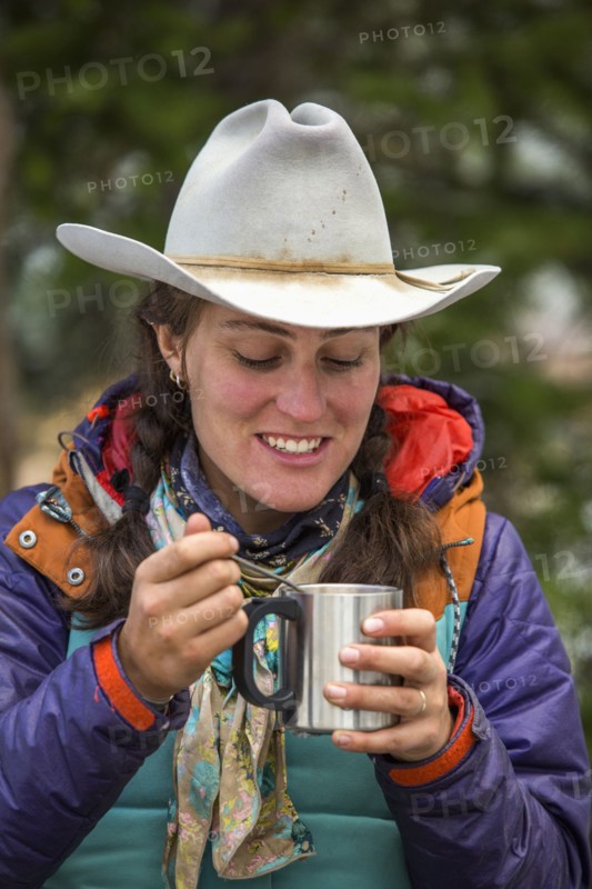 Caucasian woman using spoon with metal cup in winter