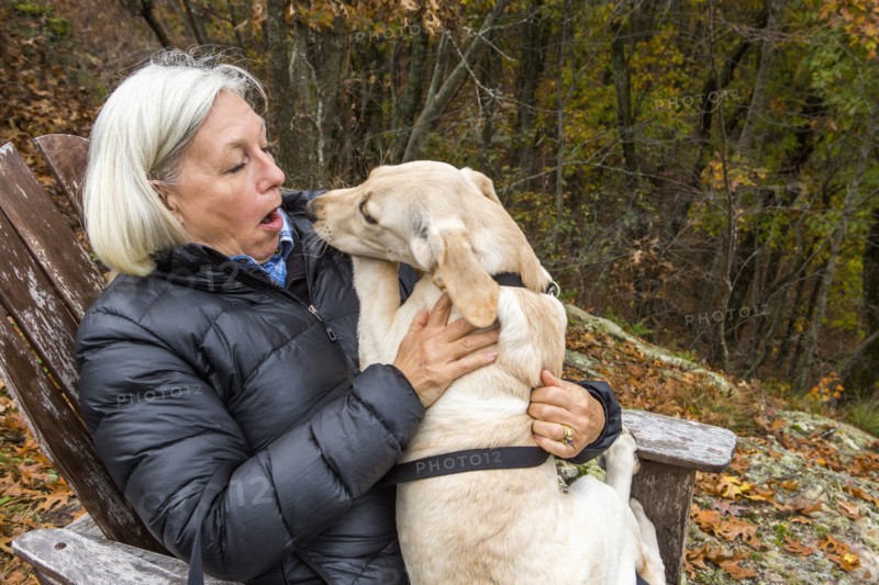 Caucasian woman holding dog in lap outdoors