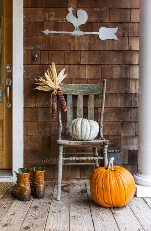 Pumpkins and corn on porch with boots in autumn