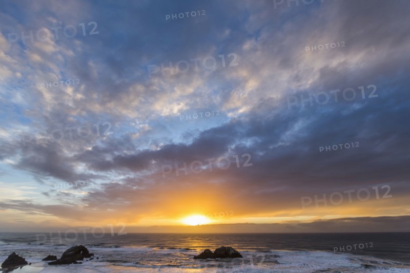 Rocks in ocean at sunset