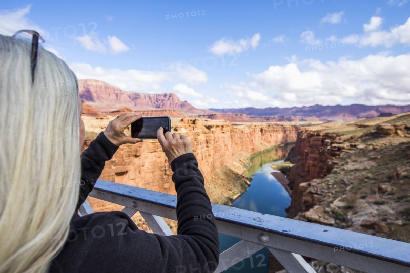 Caucasian woman photographing canyon river with cell phone