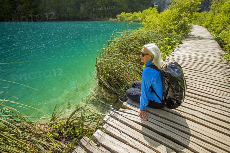 Older Caucasian woman sitting on wooden pathway near water