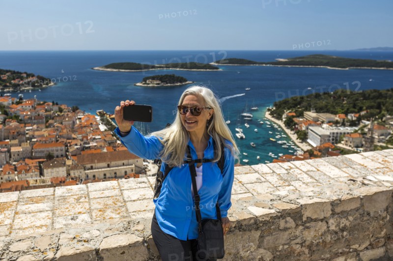 Caucasian woman posing for cell phone selfie with scenic view of ocean