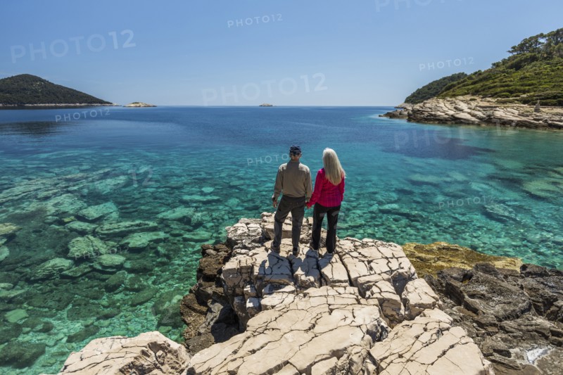 Caucasian couple standing on rock admiring lake
