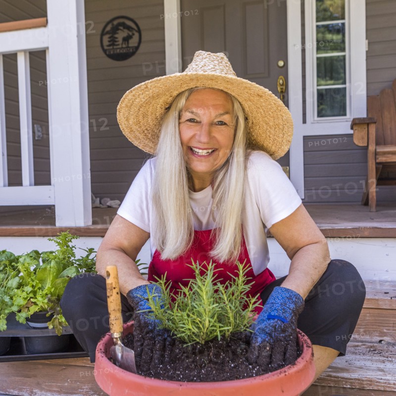 Caucasian woman planting seedling on front stoop