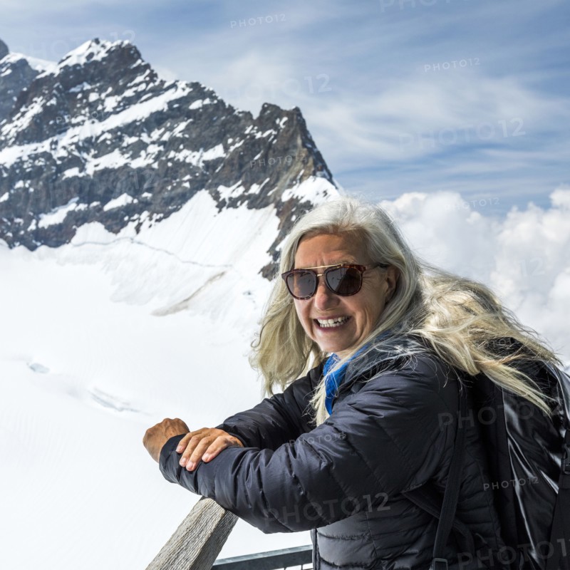 Portrait of smiling Caucasian woman leaning on railing near mountains