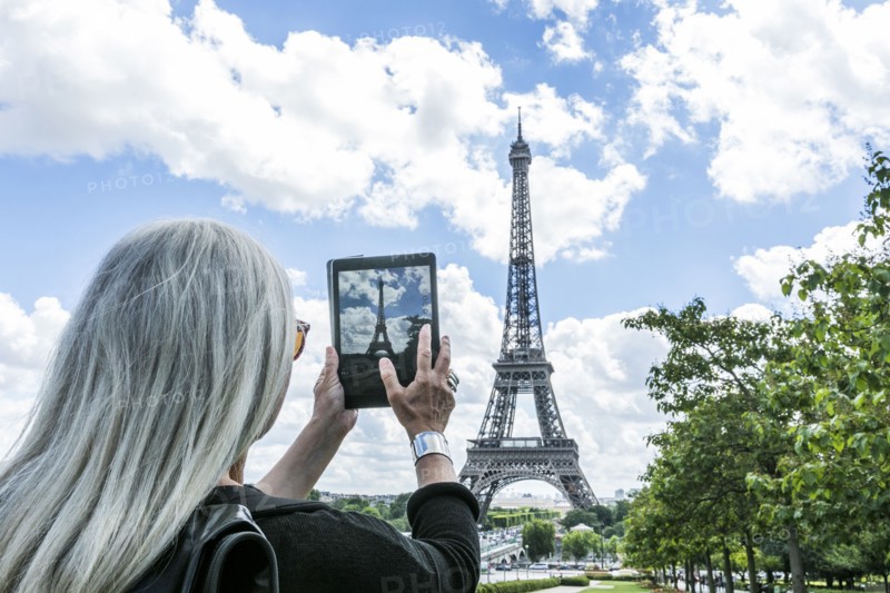 Caucasian woman photographing Eiffel Tower with digital tablet