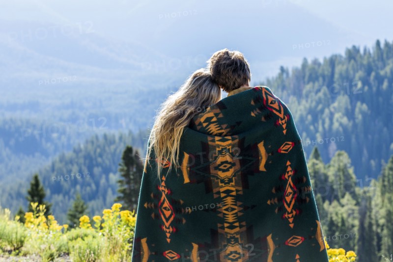 Caucasian couple wrapped in blanket admiring scenic view of landscape