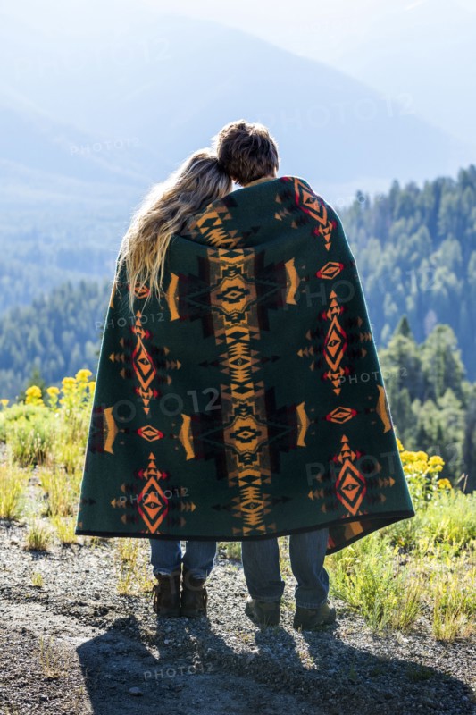 Caucasian couple wrapped in blanket admiring scenic view of landscape
