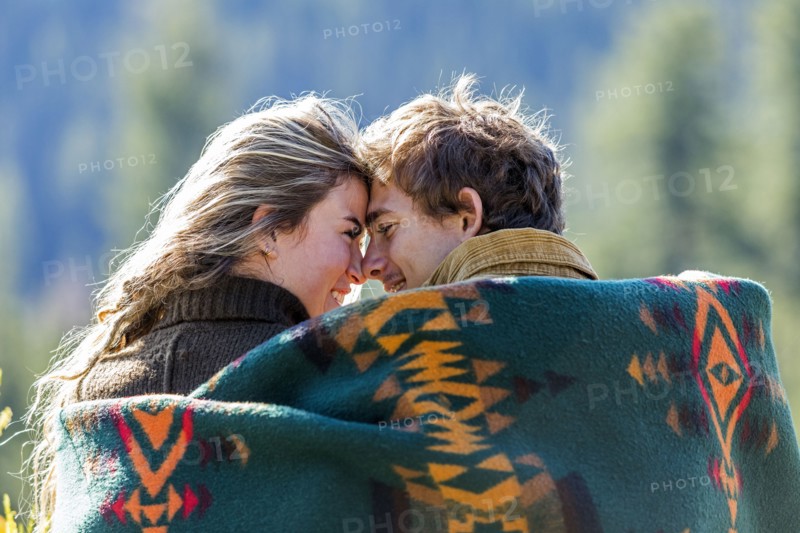 Caucasian couple wrapped in blanket rubbing noses