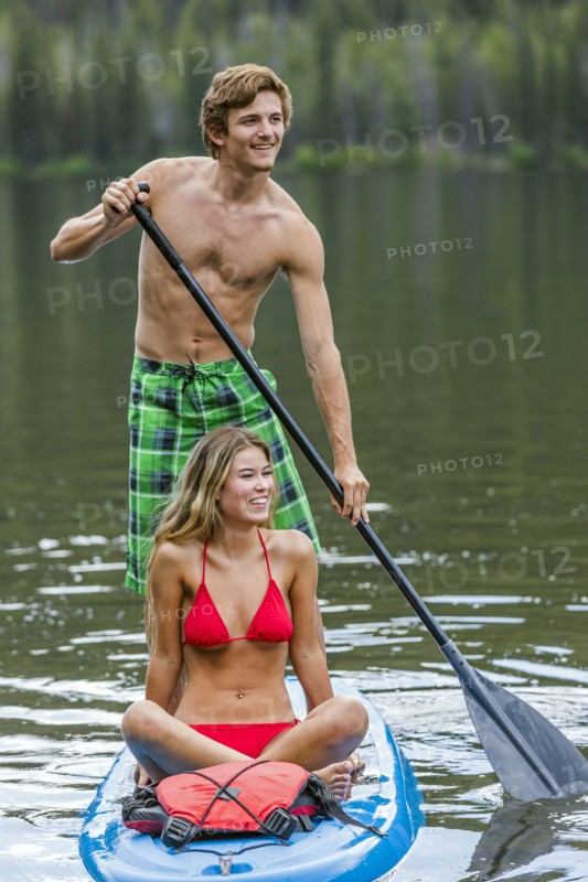 Caucasian couple riding paddleboard