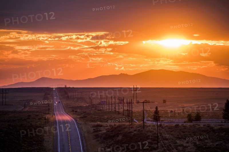 Cars driving on remote road at sunset