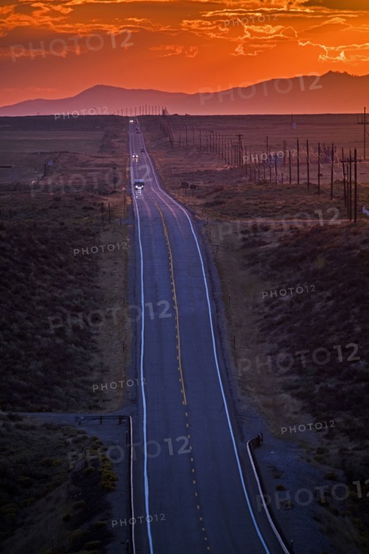 Cars driving on remote road at sunset