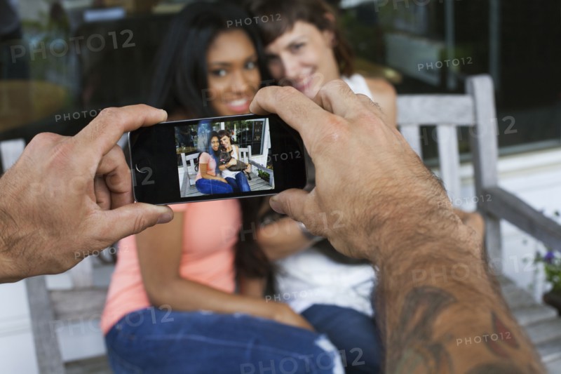 Man photographing women with cell phone
