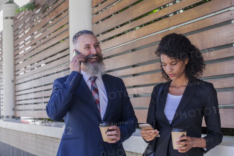 Business people standing outdoors using cell phones