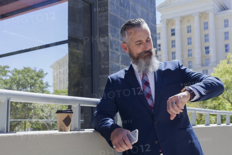 Caucasian businessman checking the time on wristwatch outdoors