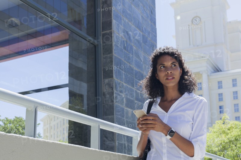 Mixed Race businesswoman texting on cell phone outdoors