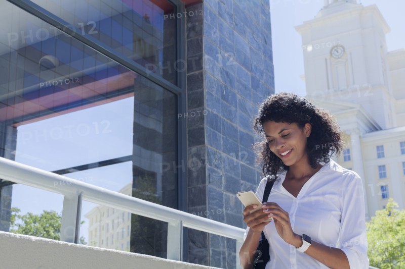 Mixed Race businesswoman texting on cell phone outdoors