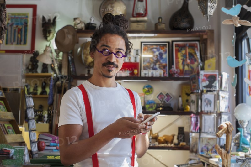 Curious mixed race man wearing suspenders texting on cell phone