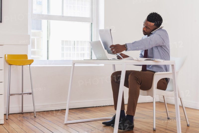 Black businessman talking on cell phone and reading notepad