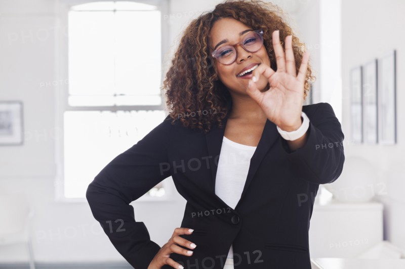 Mixed race woman gesturing okay in gallery