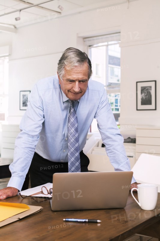Caucasian businessman leaning on table using laptop