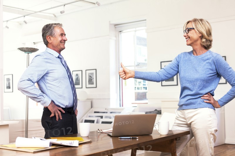 Caucasian businesswoman gesturing thumbs-up to businessman