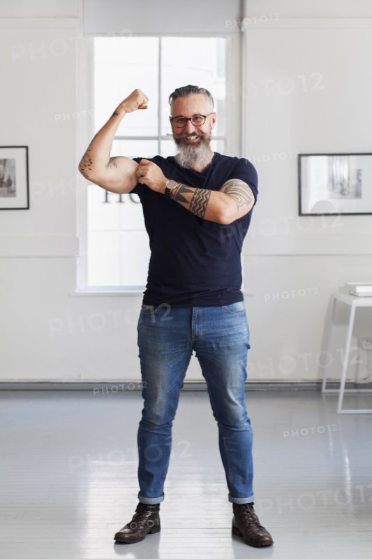 Smiling muscular Caucasian hipster man flexing biceps