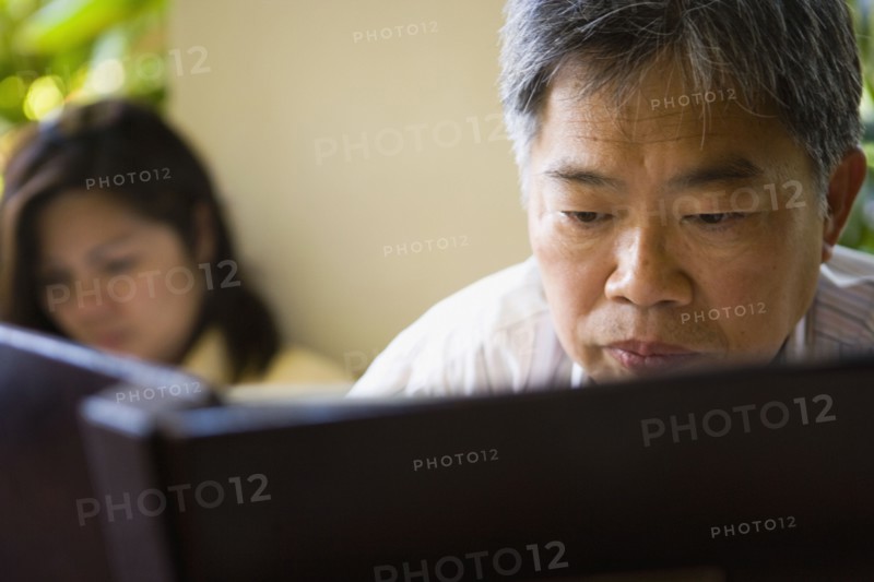 Mature Asian man reading book
