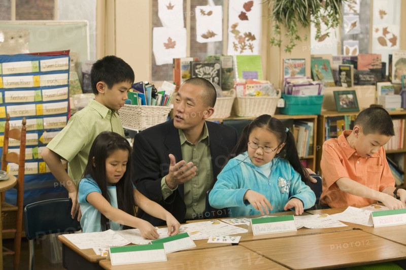 Asian school teacher helping students