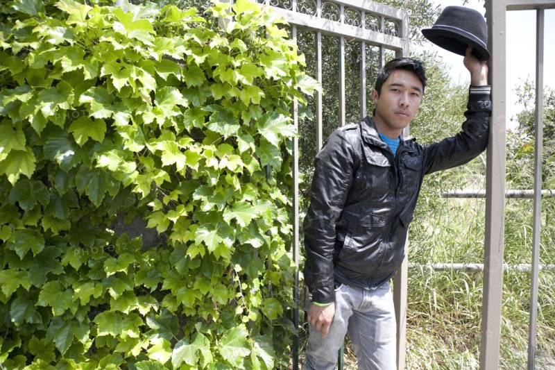 Mixed race teenage boy leaning against gate and looking serious