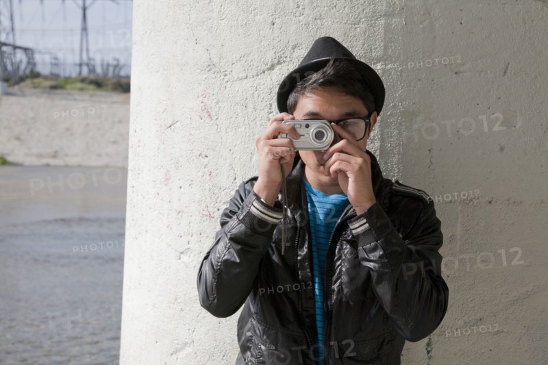 Mixed race teenage boy taking photograph with digital camera