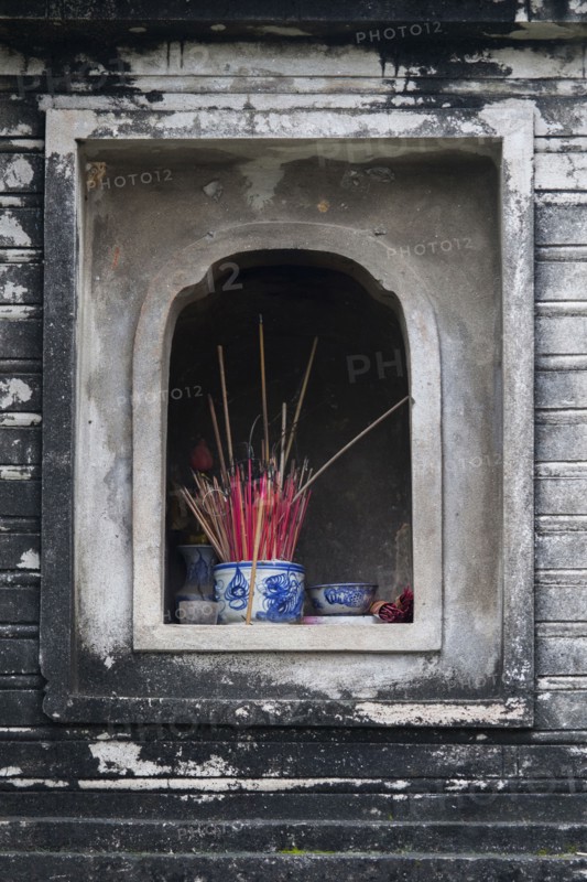 Incense in wall alcove shrine of Buddhist temple