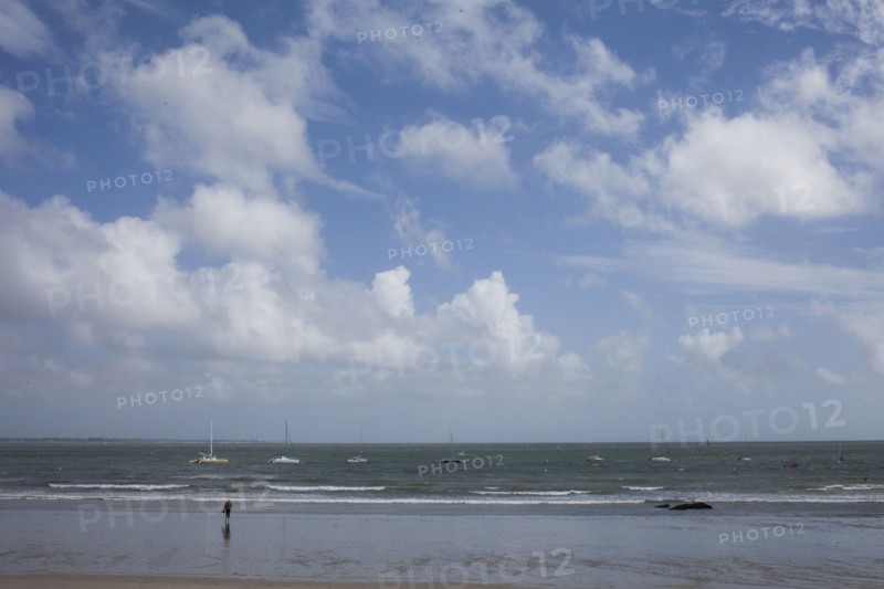 Tourist standing in waves on beach