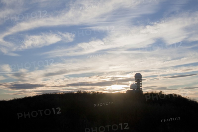 Silo on rural hilltop under cloudy sky