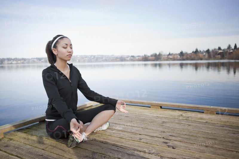 Mixed race woman practicing yoga on pier