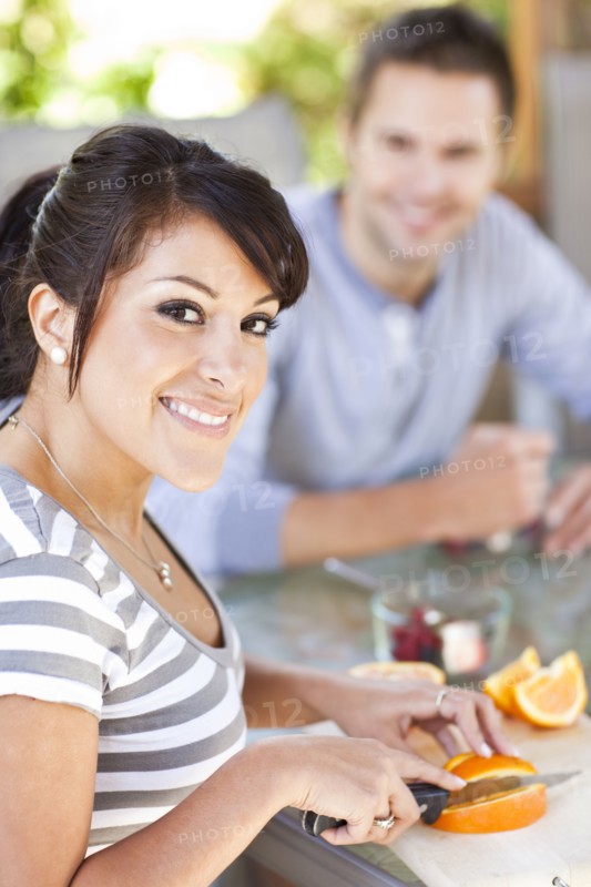 Hispanic woman slicing oranges on patio