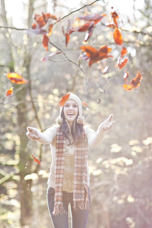 Mixed race woman in cap playing in autumn leaves