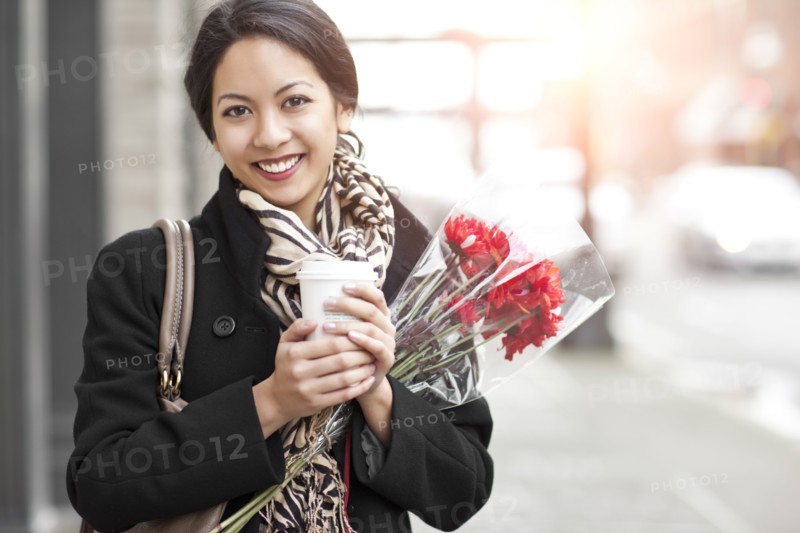 Mixed race woman holding coffee and bouquet of flowers