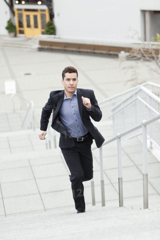 Mixed race businessman running up stairs