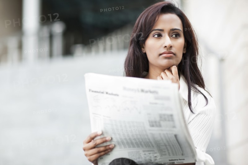 Indian businesswoman reading newspaper outdoors
