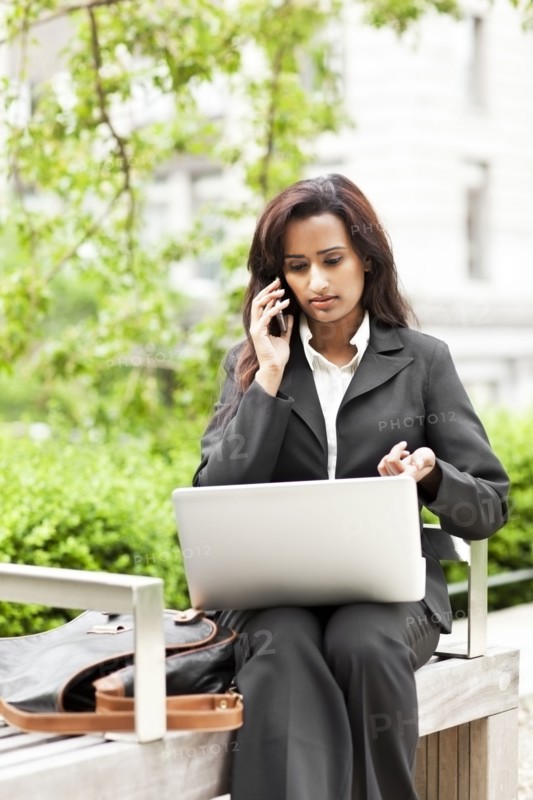 Indian businesswoman using laptop outdoors
