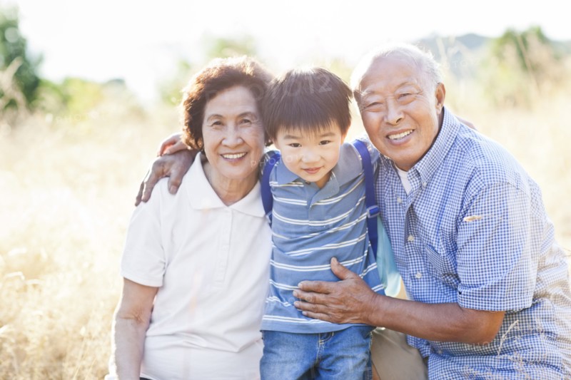 Chinese grandparents in field with grandson