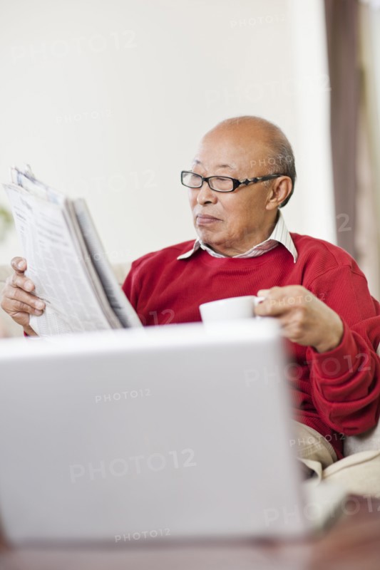 Chinese man reading newspaper and drinking coffee